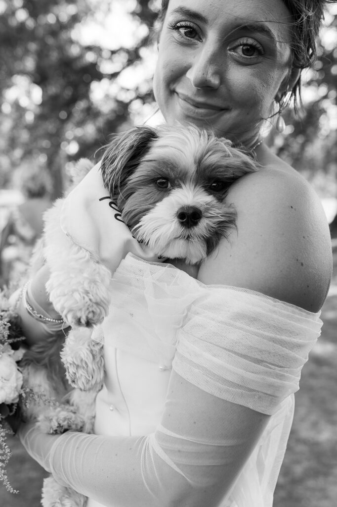 A Bride holds her dog to her chest at her Kahkwa Country Club wedding reception