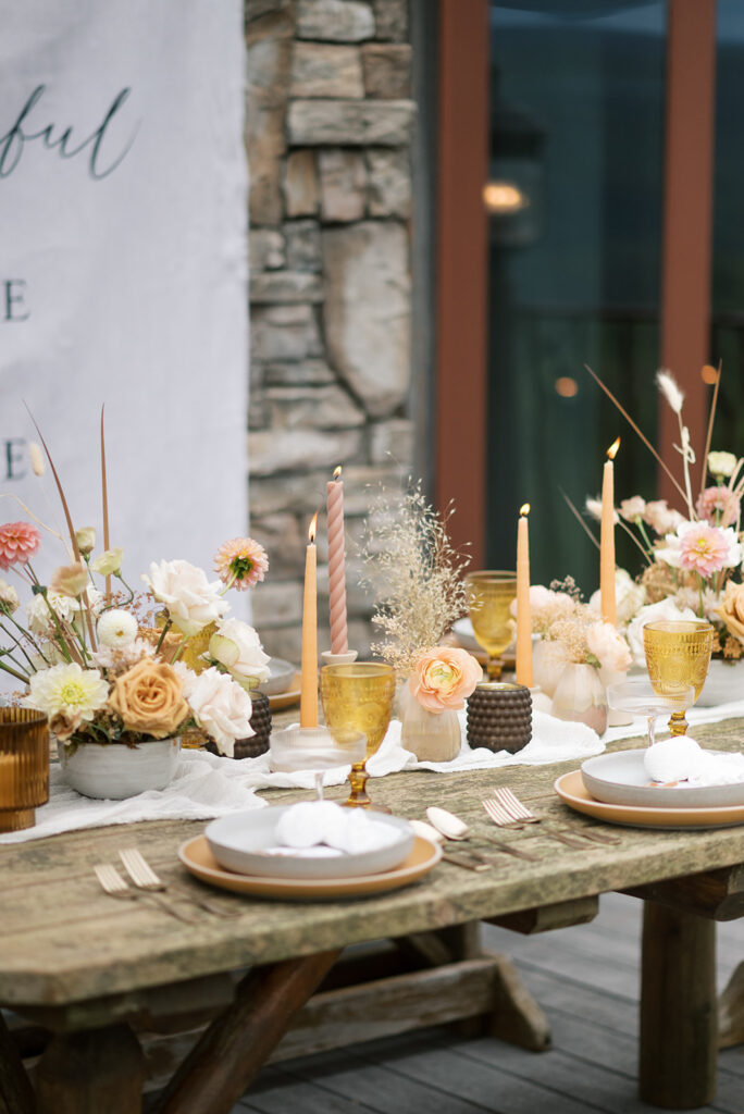 Reception table decor featuring vintage glasses, tapered candles, and floral arrangements of dusty rose & neutrals at a Cades Cove wedding