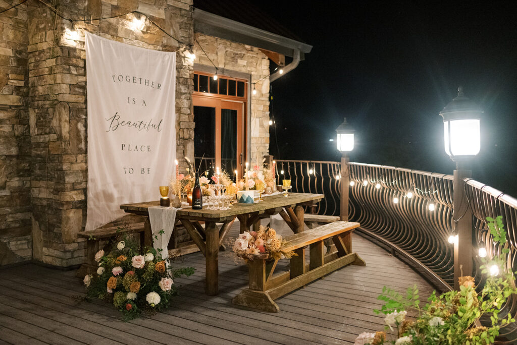 An ambient wedding reception tablescape is shown on a balcony at night overlooking the Smoky Mountains following weddings in cades cove